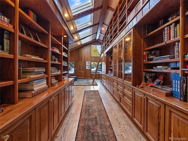 unfurnished office featuring light hardwood / wood-style flooring, coffered ceiling, built in features, lofted ceiling with skylight, and wooden walls