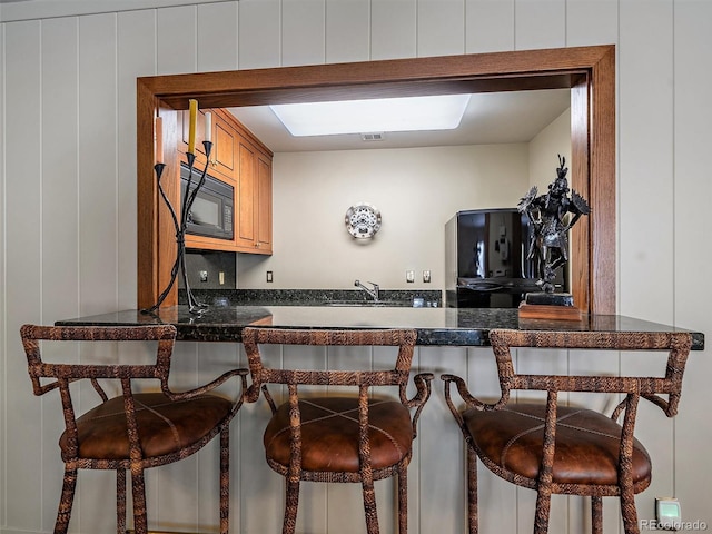 kitchen featuring sink, a kitchen bar, and black microwave