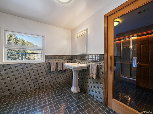 bathroom featuring tile flooring, a shower with shower door, and tile walls