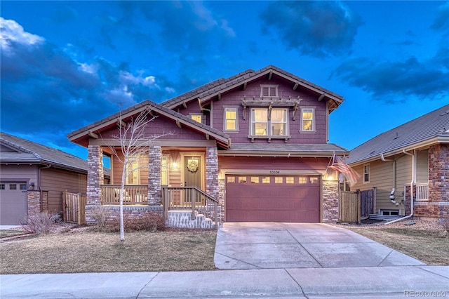 view of front of home with driveway, stone siding, an attached garage, and a porch