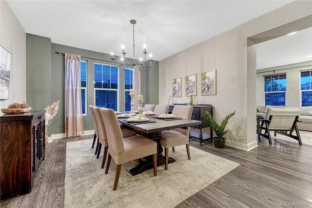 dining area featuring baseboards, an inviting chandelier, and wood finished floors