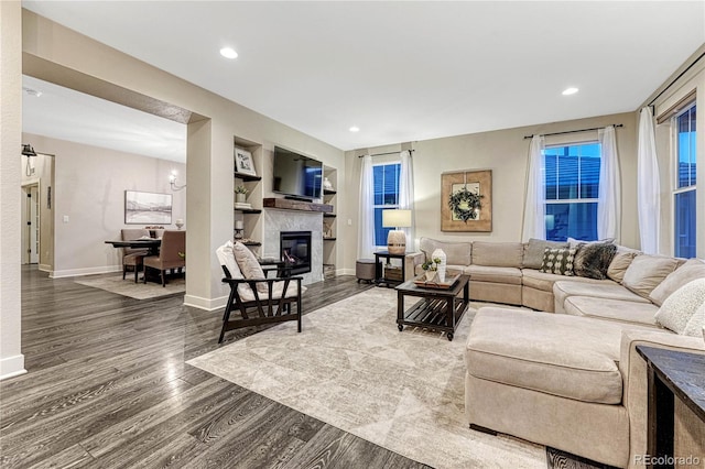 living room with built in shelves, recessed lighting, a premium fireplace, wood finished floors, and baseboards