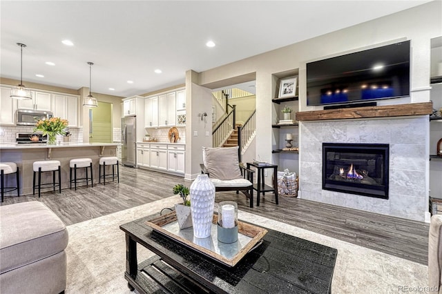 living area featuring stairway, recessed lighting, a fireplace, and light wood-style flooring