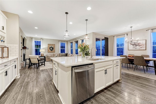 kitchen featuring a sink, light countertops, stainless steel dishwasher, dark wood-style floors, and an island with sink