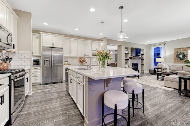 kitchen with open floor plan, appliances with stainless steel finishes, light wood-type flooring, and a sink