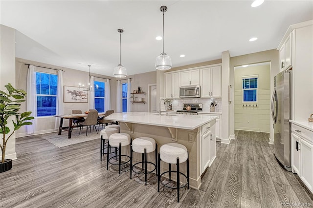 kitchen featuring stainless steel appliances, wood finished floors, a sink, a kitchen breakfast bar, and light countertops