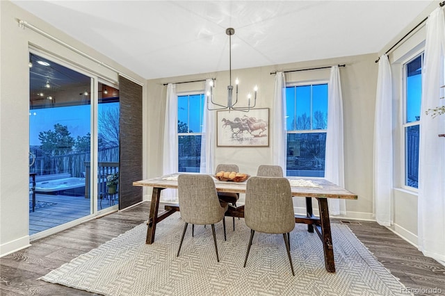 dining space with baseboards, a chandelier, and wood finished floors