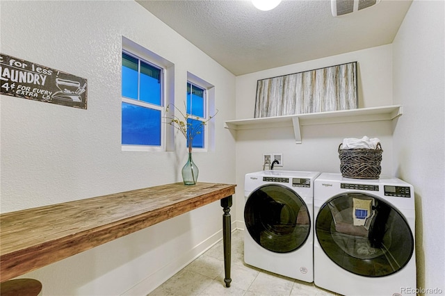 washroom featuring laundry area, light tile patterned floors, visible vents, a textured ceiling, and washing machine and dryer