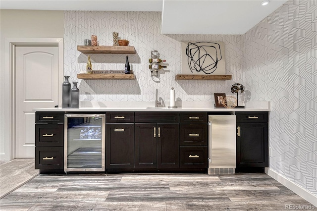 bar featuring wine cooler, high quality fridge, light wood finished floors, and wallpapered walls