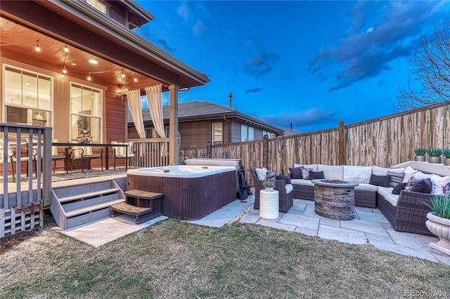 view of patio with a hot tub, fence, a wooden deck, and an outdoor living space with a fire pit