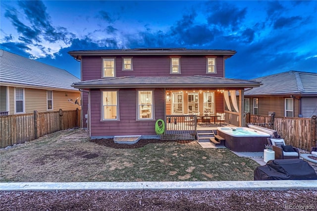 view of front of house with roof mounted solar panels, a fenced backyard, a wooden deck, and a hot tub