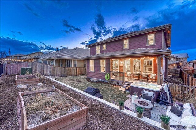 back of house with a patio area, a fenced backyard, a vegetable garden, and an outdoor living space with a fire pit