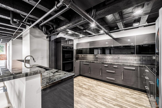 201 Lamkin St Unit 204, Pueblo, CO 81003 - kitchen featuring light wood-style flooring, backsplash, dark stone countertops, modern cabinets, and a peninsula