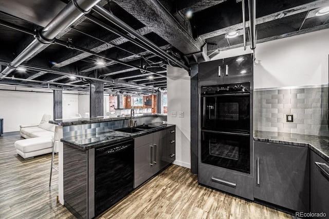 201 Lamkin St Unit 204, Pueblo, CO 81003 - kitchen featuring black appliances, wood finished floors, a breakfast bar, a peninsula, and dark cabinets