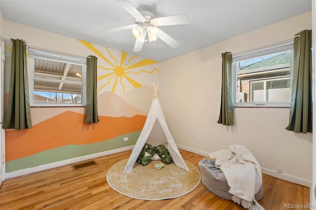 bedroom with multiple windows, wood-type flooring, and ceiling fan