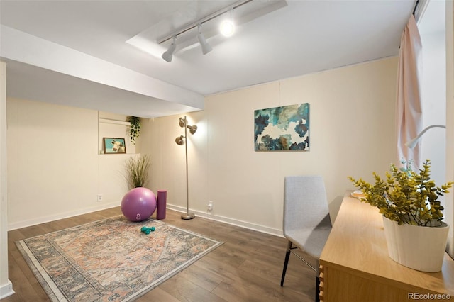 exercise room with rail lighting and dark wood-type flooring