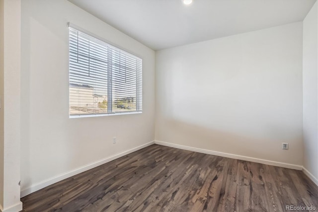 spare room featuring dark wood-style floors and baseboards