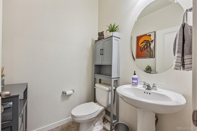 half bathroom featuring tile patterned flooring, baseboards, and toilet