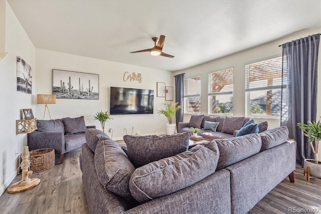 living room featuring baseboards, a ceiling fan, and wood finished floors