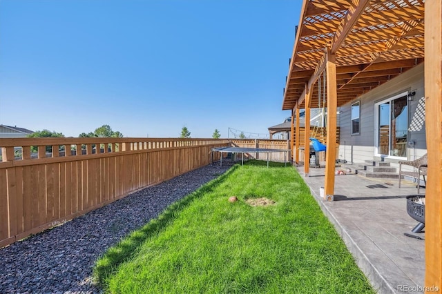 view of yard featuring a trampoline, entry steps, a patio area, and a fenced backyard