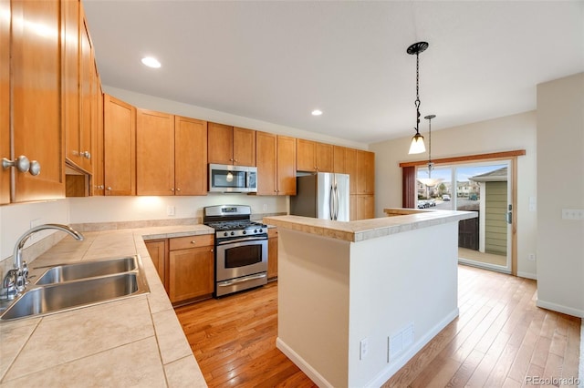 22813 E Briarwood Pl, Aurora, CO 80016 - kitchen with appliances with stainless steel finishes, light wood-style floors, a center island, decorative light fixtures, and recessed lighting