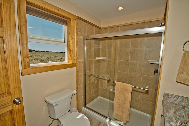 bathroom featuring a shower with door and toilet