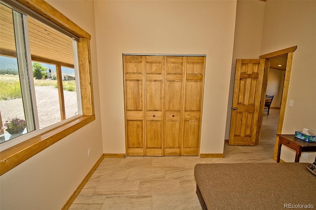 bedroom with a closet, light tile patterned floors, and a towering ceiling