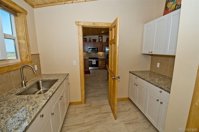 kitchen featuring light tile patterned floors, white cabinets, backsplash, stainless steel appliances, and sink