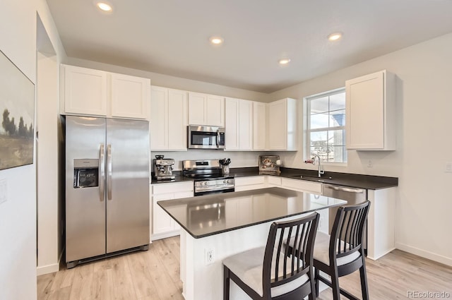 kitchen featuring a center island, white cabinets, sink, light hardwood / wood-style flooring, and stainless steel appliances