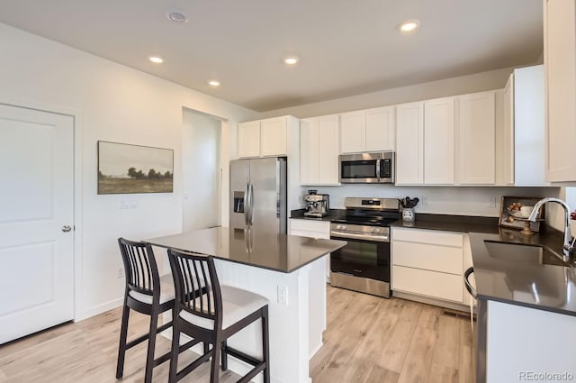 kitchen with a center island, sink, stainless steel appliances, light hardwood / wood-style flooring, and white cabinets