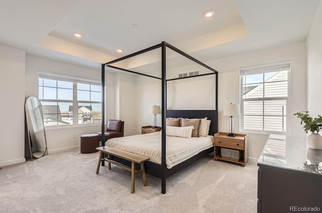 carpeted bedroom with a tray ceiling and multiple windows