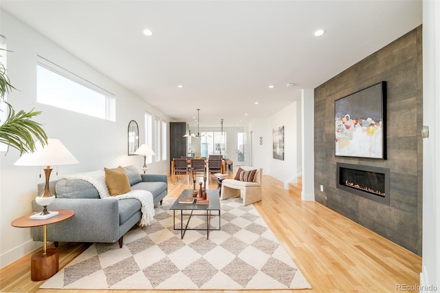 living room featuring a tile fireplace and light wood-type flooring