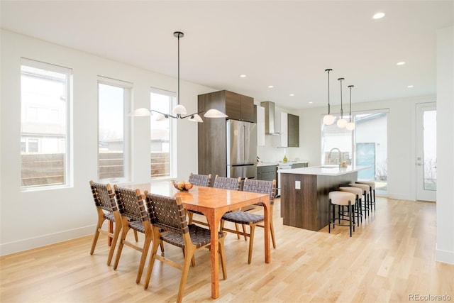 dining space with a healthy amount of sunlight, sink, and light hardwood / wood-style flooring