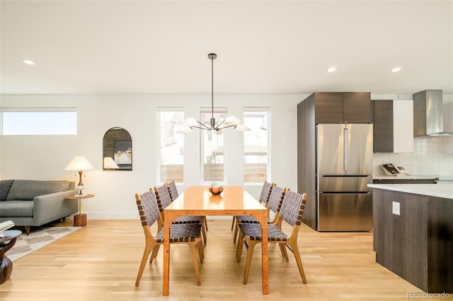 dining area featuring a healthy amount of sunlight, a chandelier, and light wood-type flooring