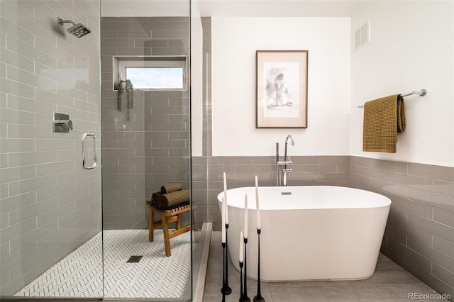 bathroom featuring tile patterned floors, separate shower and tub, and tile walls