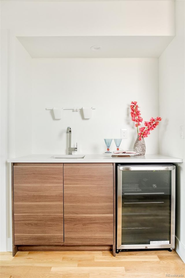 bar with wine cooler, sink, and light hardwood / wood-style flooring