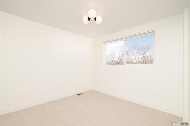 carpeted empty room featuring a chandelier