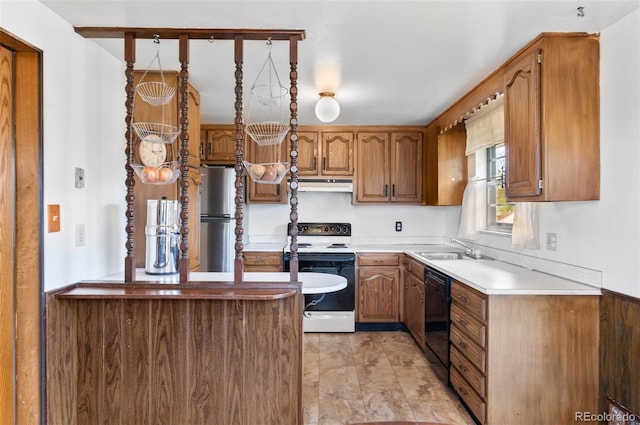 kitchen with range with electric cooktop, freestanding refrigerator, a sink, under cabinet range hood, and brown cabinetry