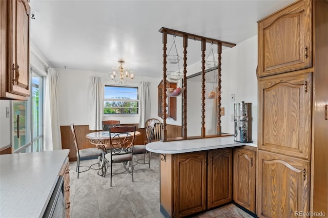 kitchen featuring a peninsula, plenty of natural light, light countertops, a chandelier, and a wainscoted wall