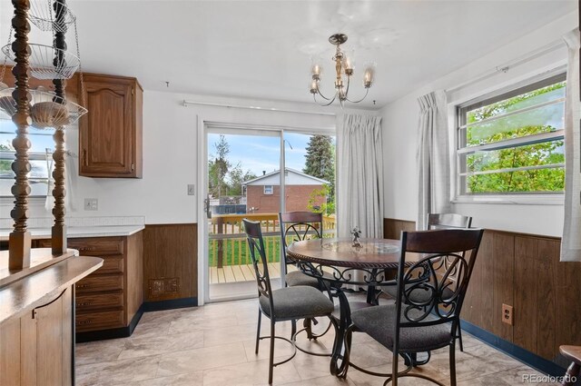 dining room with a wainscoted wall, plenty of natural light, wooden walls, and a chandelier