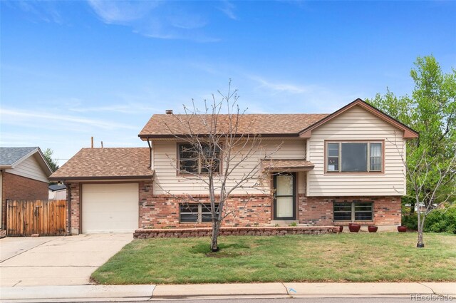 bi-level home with concrete driveway, an attached garage, brick siding, and a shingled roof