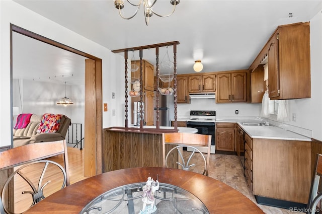 kitchen with electric range, a sink, brown cabinetry, light countertops, and a chandelier