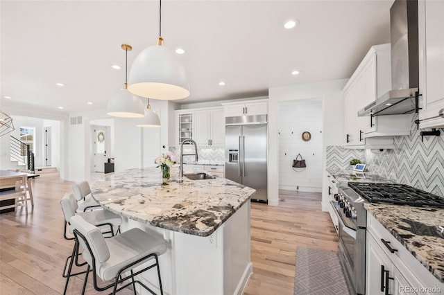 10757 Timberdash Ave, Highlands Ranch, CO 80126 - kitchen featuring high end appliances, wall chimney exhaust hood, light stone counters, tasteful backsplash, and a breakfast bar