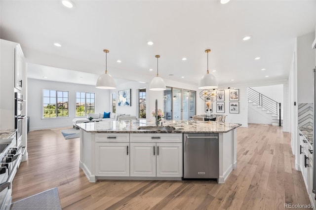 10757 Timberdash Ave, Highlands Ranch, CO 80126 - kitchen featuring open floor plan, white cabinets, light wood-type flooring, a kitchen island with sink, and recessed lighting