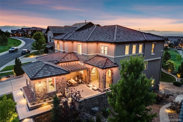 10757 Timberdash Ave, Highlands Ranch, CO 80126 - back of property at dusk featuring stucco siding, a pergola, and stone siding