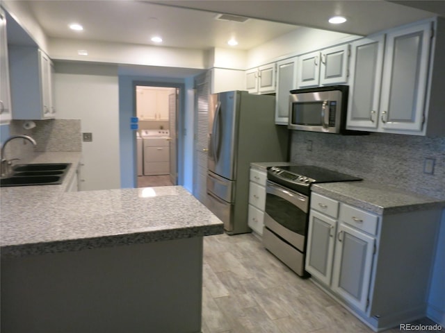 1900 E Girard Pl Unit 203, Englewood, CO 80113 - kitchen with appliances with stainless steel finishes, washer and dryer, tasteful backsplash, recessed lighting, and a peninsula