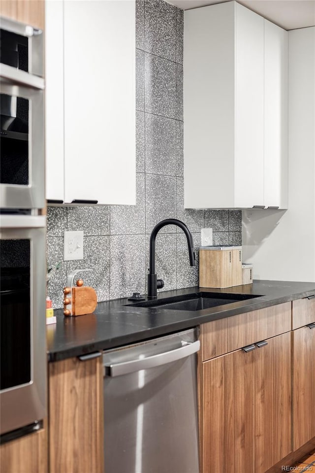 1330 Olive St, Denver, CO 80220 - kitchen with stainless steel appliances, a sink, modern cabinets, dark countertops, and decorative backsplash