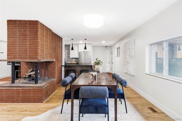 1330 Olive St, Denver, CO 80220 - dining area with light wood-style floors, baseboards, and a brick fireplace