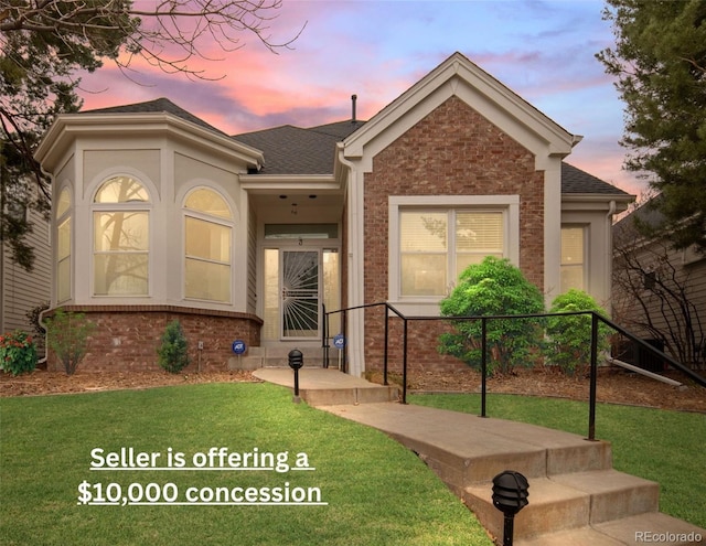 ranch-style home featuring a shingled roof, brick siding, and a front lawn