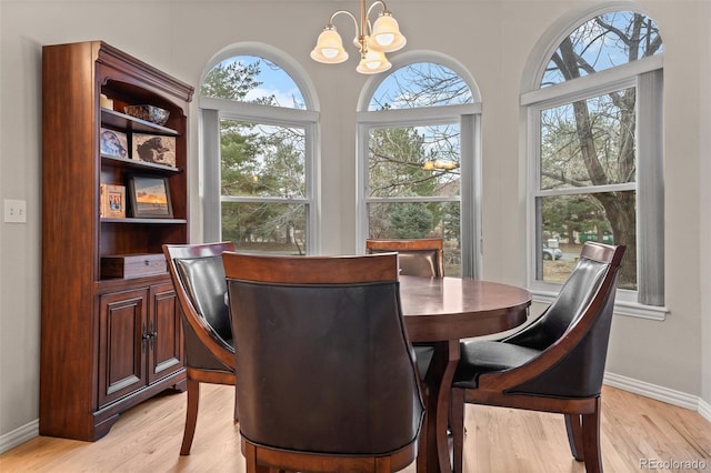 dining area with an inviting chandelier, baseboards, and light wood-type flooring